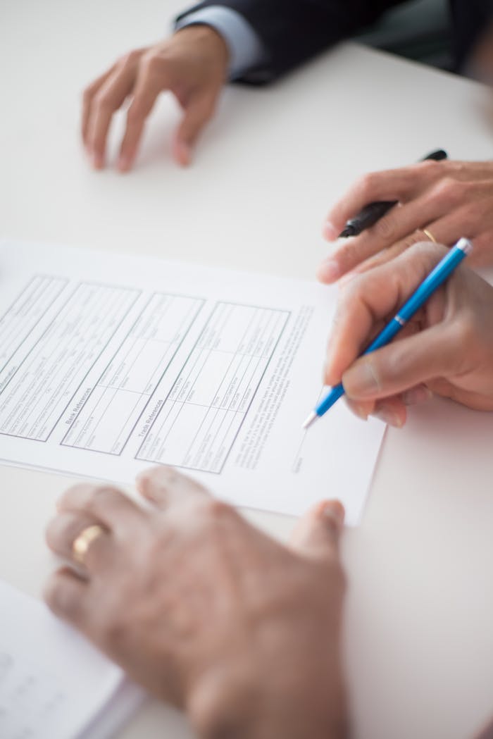 Segunda Oportunidad: cómo liberarte de deudas paso a paso Close-up of hands signing a business document on a white surface with a pen.